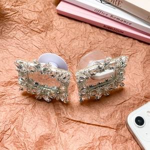 Detail of crystal encrusted rectangular phone grip with folding stand on paper background