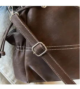 Detail of dark brown leather tote featuring white stitching and silver adjustment buckle