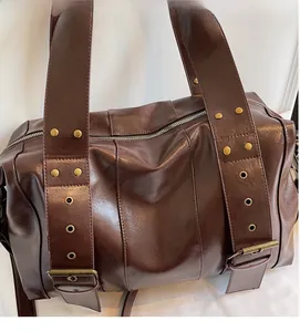 Close-up of vintage brown leather tote bag with retro metal rivets and zipper detail