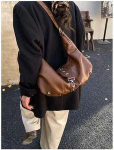 Brown hobo bag with star rivets shown from a back view on a model in street style
