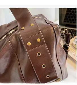 Detailed close-up of brown vintage leather bag with decorative bronze studs and rivets