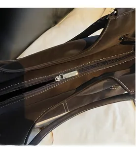 Close-up of the smooth silver zipper closure and white stitching on a dark brown leather tote bag