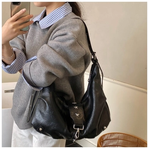 Detail of black vintage PU leather hobo bag with silver star studs and wide strap