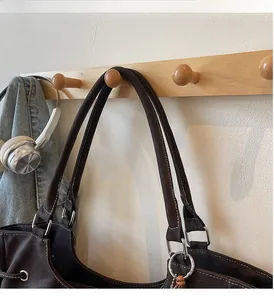 Detail of dark brown leather tote bag with white stitching and silver metal hardware rings