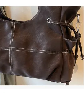 Detail of dark brown leather tote bag with white contrast stitching and silver eyelet