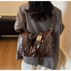 Detail of dark brown leather tote bag with bronze hardware and adjustable wide shoulder strap