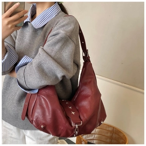 Detail of dark burgundy hobo bag with star-shaped metal studs and adjustable shoulder strap