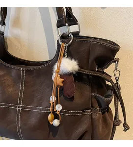 Detail of glove-shaped bag charm with plush trim, star pendant, and amber beads