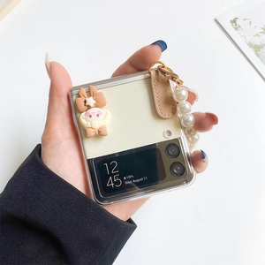 Detail of Galaxy Z Flip case featuring white pearl wrist strap and cute cartoon ornament