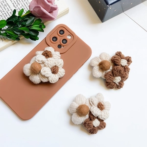 Macro detail of plush knitted flower phone grips in coffee tones with a 3D texture