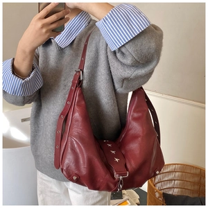 Detail of burgundy shoulder bag featuring star metal studs and adjustable eyelet strap