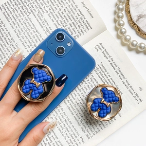 Detailed macro of blue quilted teddy bear phone grip with golden bow and metal trim