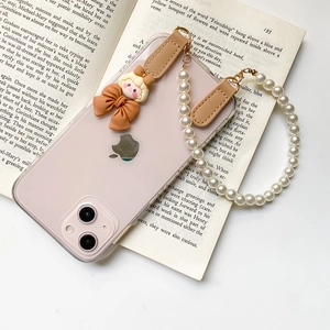 Détail de la coque iPhone transparente avec bracelet en perles et breloque nœud brun