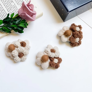 Macro view of three handmade knitted flower phone grips with soft plush texture details