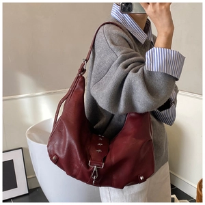 Close-up of deep red tote bag with silver star buckle and glossy leather texture