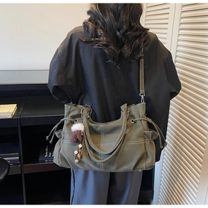 Olivgrüne Tragetasche Detail mit seitlichem Kordelzug und einem dekorativen Taschenanhänger