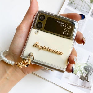 Detail showing elegant pearl bracelet strap and golden Sagittarius text on phone case
