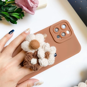 Close-up of 3D knitted flower decorations on a coffee brown phone case with camera protection