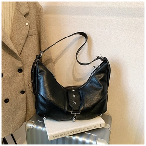 Detail of black leather hobo bag with silver star studs and adjustable shoulder strap