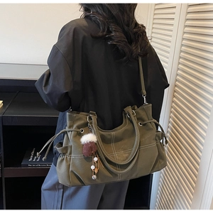 Detail der olivgrünen Tragetasche mit Kontrastnähten und Vintage-Charme-Anhänger