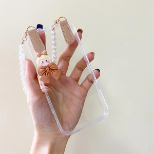 Détail de coque iPhone transparente avec bracelet en perles et breloque de dessin animé