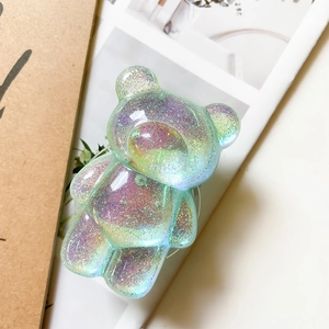 Glitter bear phone grip with holographic finish and colorful sequins on paper backdrop
