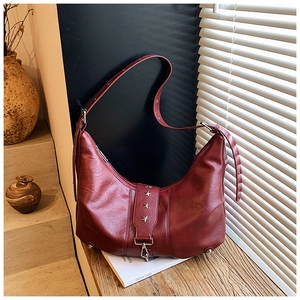 Close-up of deep red crescent bag featuring silver star studs and vintage leather texture