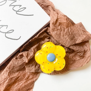 Yellow flower phone grip with blue center and colorful dots on a resin surface