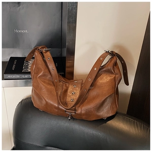 Detail of vintage brown leather tote bag with star ornament and wide strap on bench
