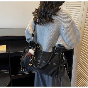 Detail der schwarzen Shopper Tasche mit weißen Kontrastnähten und Plüsch-Anhänger