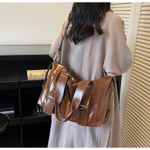 Detail of vintage brown glossy tote bag with wide handles and adjustable strap on a model