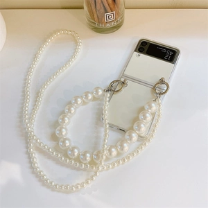 Detailed view of pearl phone strap with silver metal rings on a white folding case