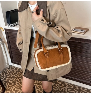 Detail of a brown suede bag with cream faux fur trim and gold metal hardware finish