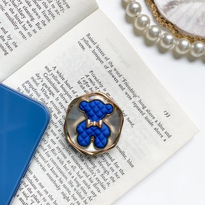 Macro detail of quilted blue bear accessory with gold bow on a vintage book background