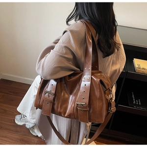 Detailed view of brown PU leather tote bag with vintage metal eyelets and wide shoulder strap