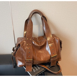 Detail of vintage caramel tote bag with brass studs and polished leather texture