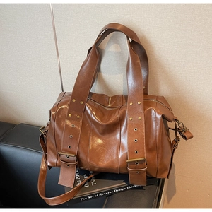 Detailed view of brown retro leather tote bag featuring bronze buckles and stylish straps