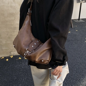 Dark brown leather vintage hobo bag with silver star rivets shown on model outdoors