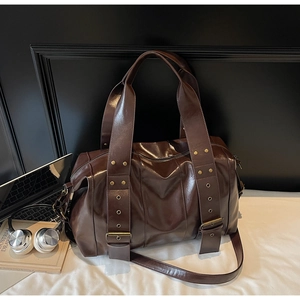 Detail view of dark brown vintage leather tote with brass rivets and adjustable strap