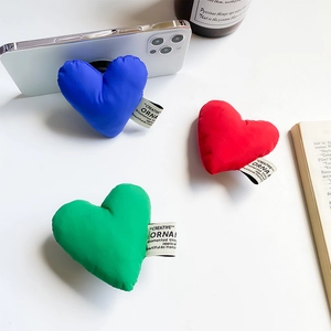 Detailed view of colorful quilted heart-shaped phone grips on a white desk