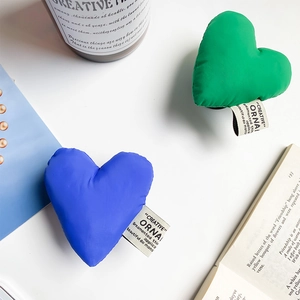 Macro detail of heart-shaped fabric phone grip with woven tag on white background