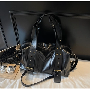 Detailed view of the large black faux leather tote bag with metallic rivet accents