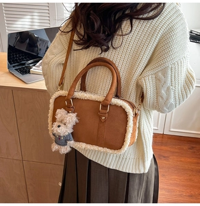 Detail view of brown suede handbag with cream faux fur trim and bear charm on model