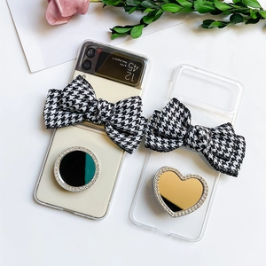 Close-up of clear Samsung Z Flip case with houndstooth bow and sparkling heart mirror
