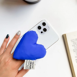 Detail of plush heart-shaped phone grip in Klein Blue with minimalist textile tag