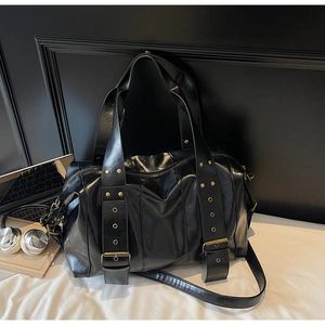 Detail of black matte leather tote bag featuring vintage metal rivets and buckle accents