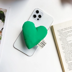 Detail of green fabric heart phone socket with a woven label on a white smartphone