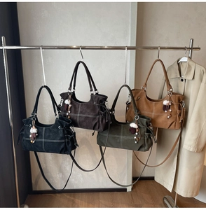 Detail view of four textured tote bags in black, green, coffee, and tan with plush charms