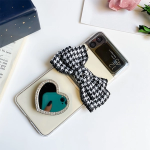 Detail of Galaxy Z Flip case with houndstooth bow and heart mirror grip on aesthetic background