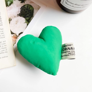 Detailed view of a plush green heart phone grip with creative label on aesthetic background